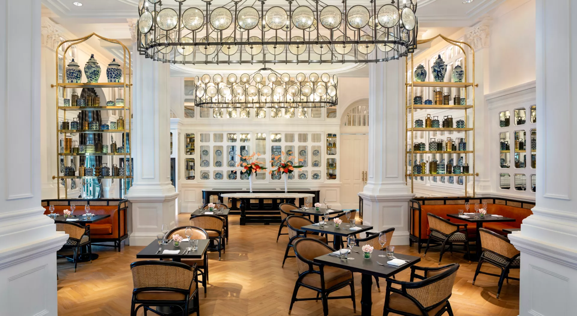 The bright Tiffin Room at Raffles Singapore, with dining tables and hanging lights