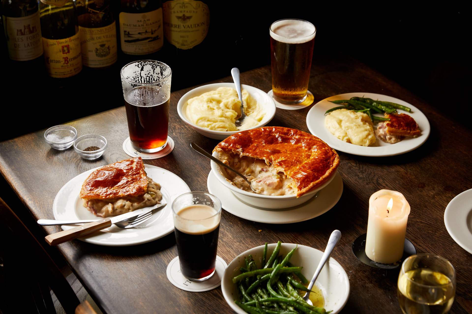 British pub dishes, pints and wine arranged on a dark wooden table at The Hawthorn