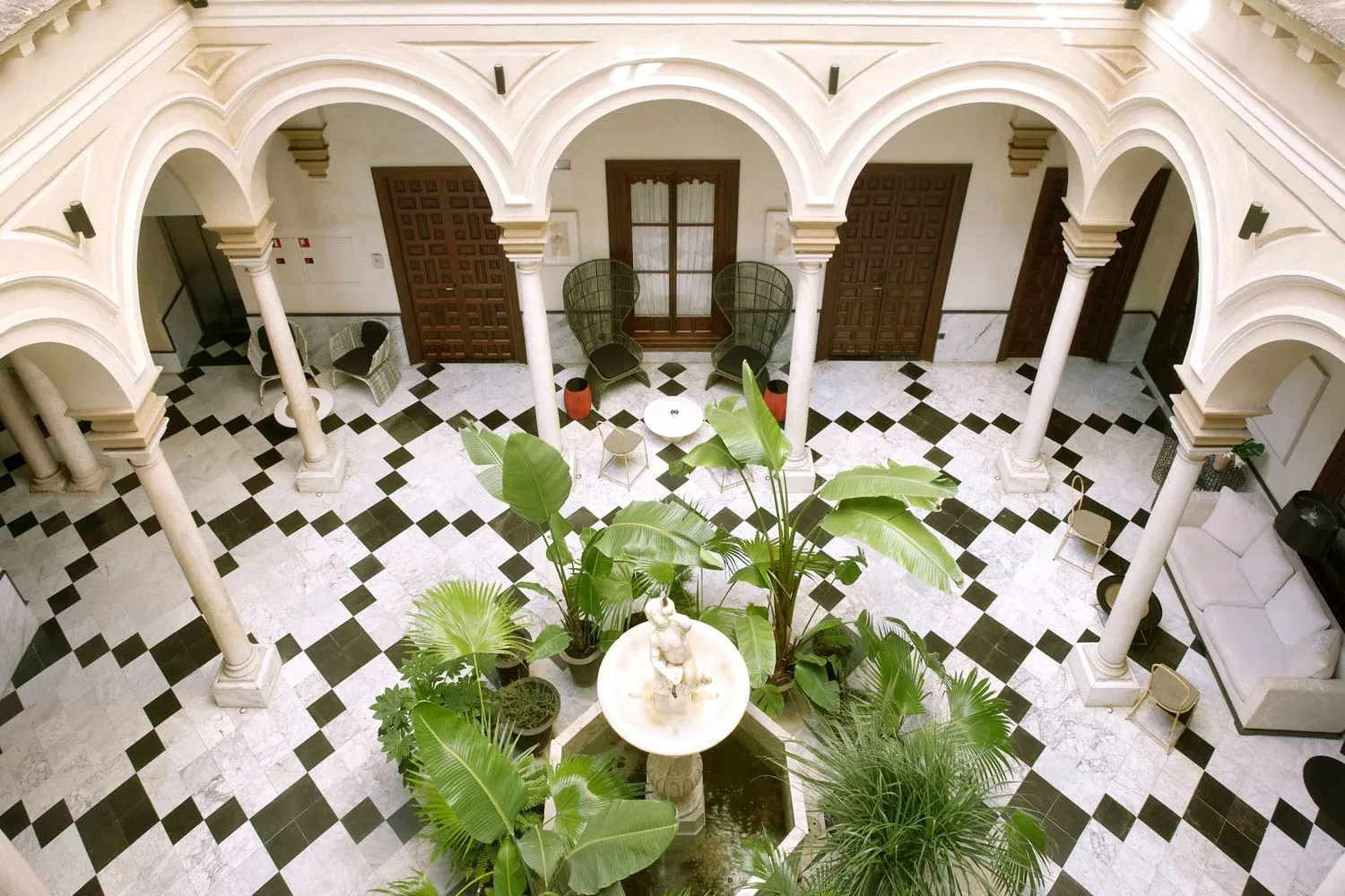 The main courtyard at Palacio Villapanés — marble columns, chequerboard floor and a central fountain