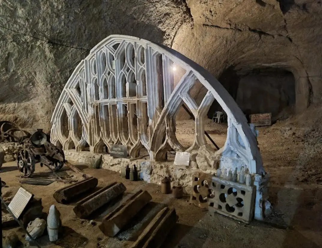 Carved Gothic window tracery in Beer stone standing inside a cavern at Beer Quarry Caves