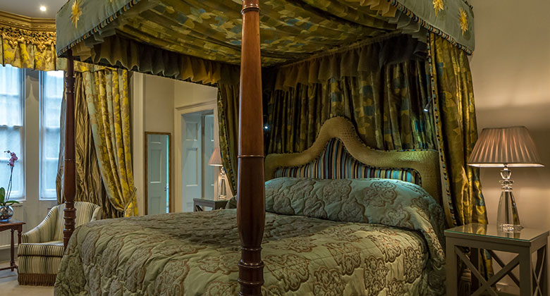 A four-poster bedroom at The George of Stamford with patterned green fabrics