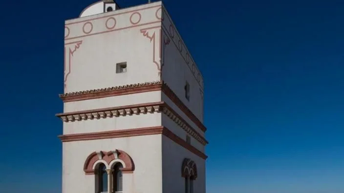 The upper stage of Torre Tavira, white and terracotta against a deep blue Cádiz sky