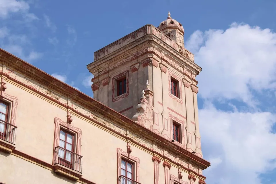 The pink and cream watchtower of Torre Tavira rising above the roofline of the Palace of the Marqueses de Recaño in Cádiz
