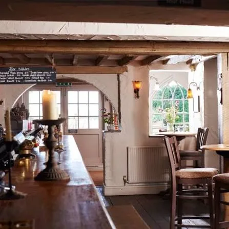The beamed bar at Botley Hill Farmhouse, with candles, exposed timber framing and a chalkboard menu