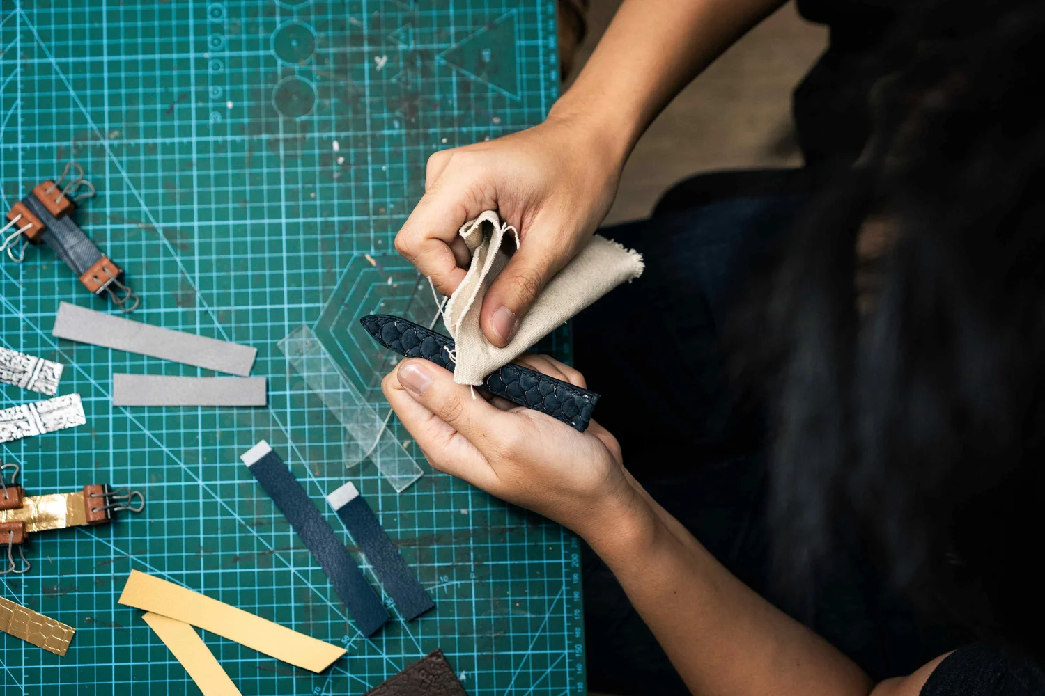 Philip Chuah works on a dark blue leather watch strap at Atelier KAI’s cutting bench