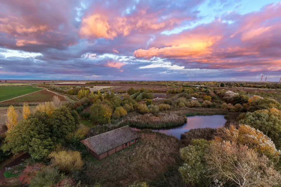 Flag Fen Archaeology Park and the surrounding Fenland landscape beneath a dramatic sunset sky