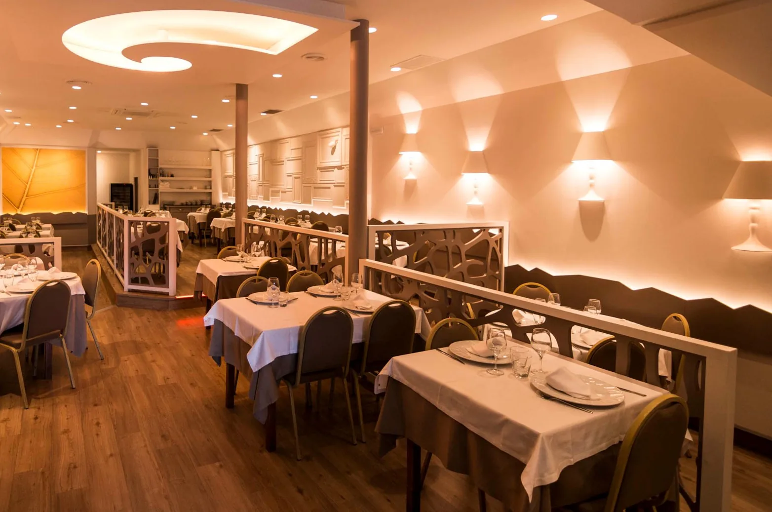 The dining room at El Racó del Cargol, set with white tablecloths beneath warm wall lights