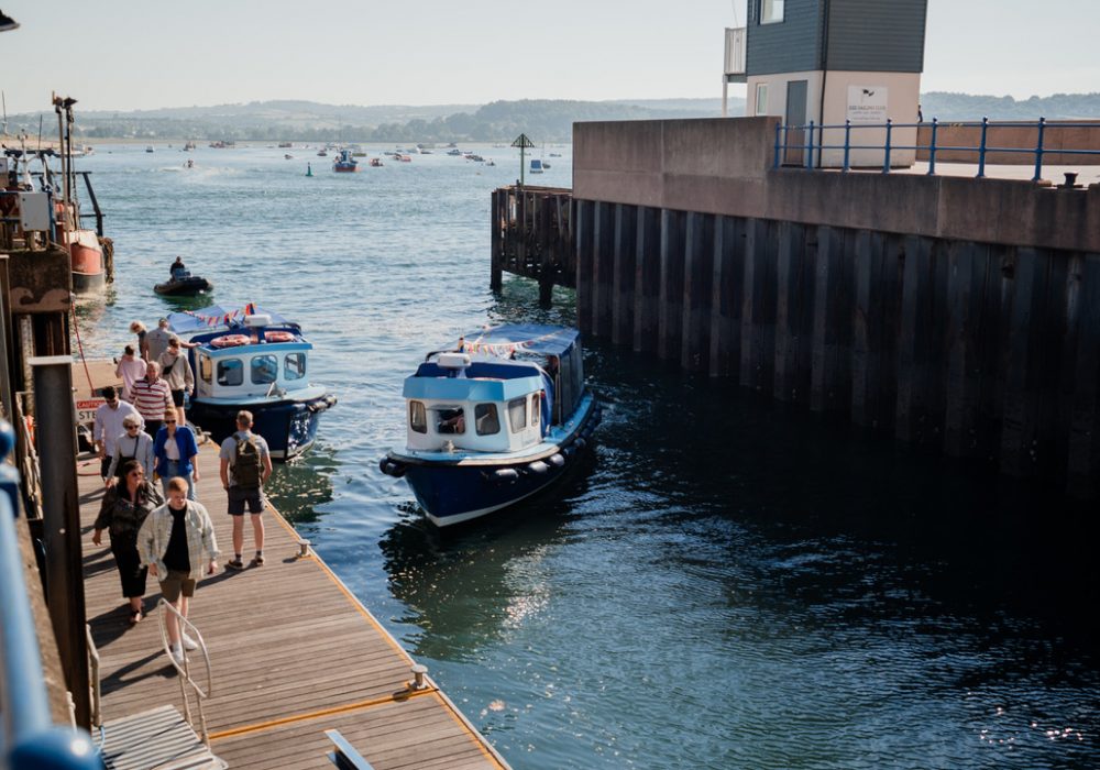 Diners walking along the visitors' pontoon at Exmouth Marina beside the blue Puffin water taxis