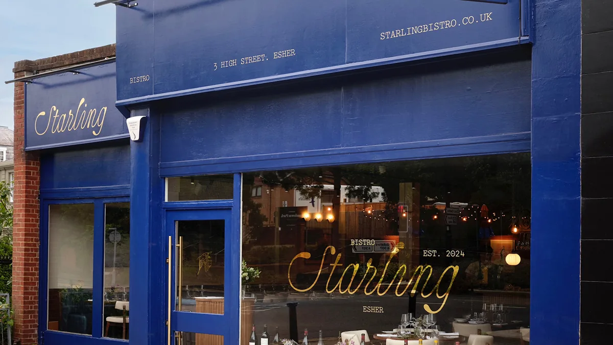 Starling — the deep blue shopfront and gold script signage on Esher High Street at dusk
