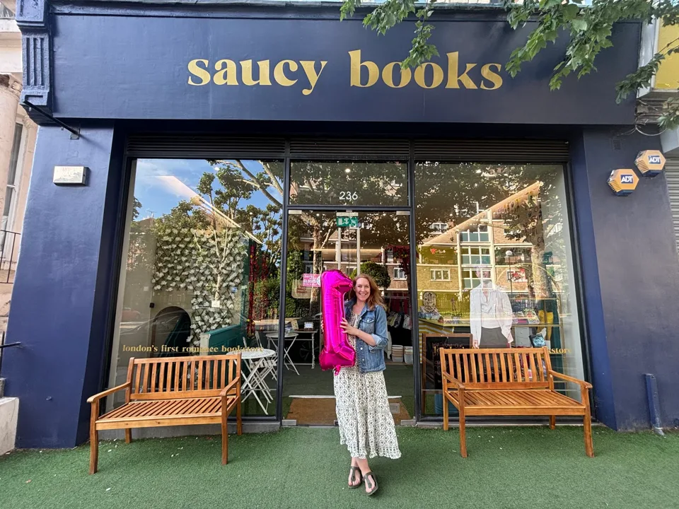 Founder Sarah Maxwell holding a pink number one balloon outside Saucy Books on Westbourne Park Road, Notting Hill