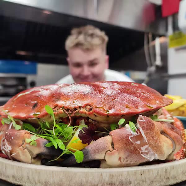 A whole dressed crab served at River Exe Café, with a chef behind it in the kitchen