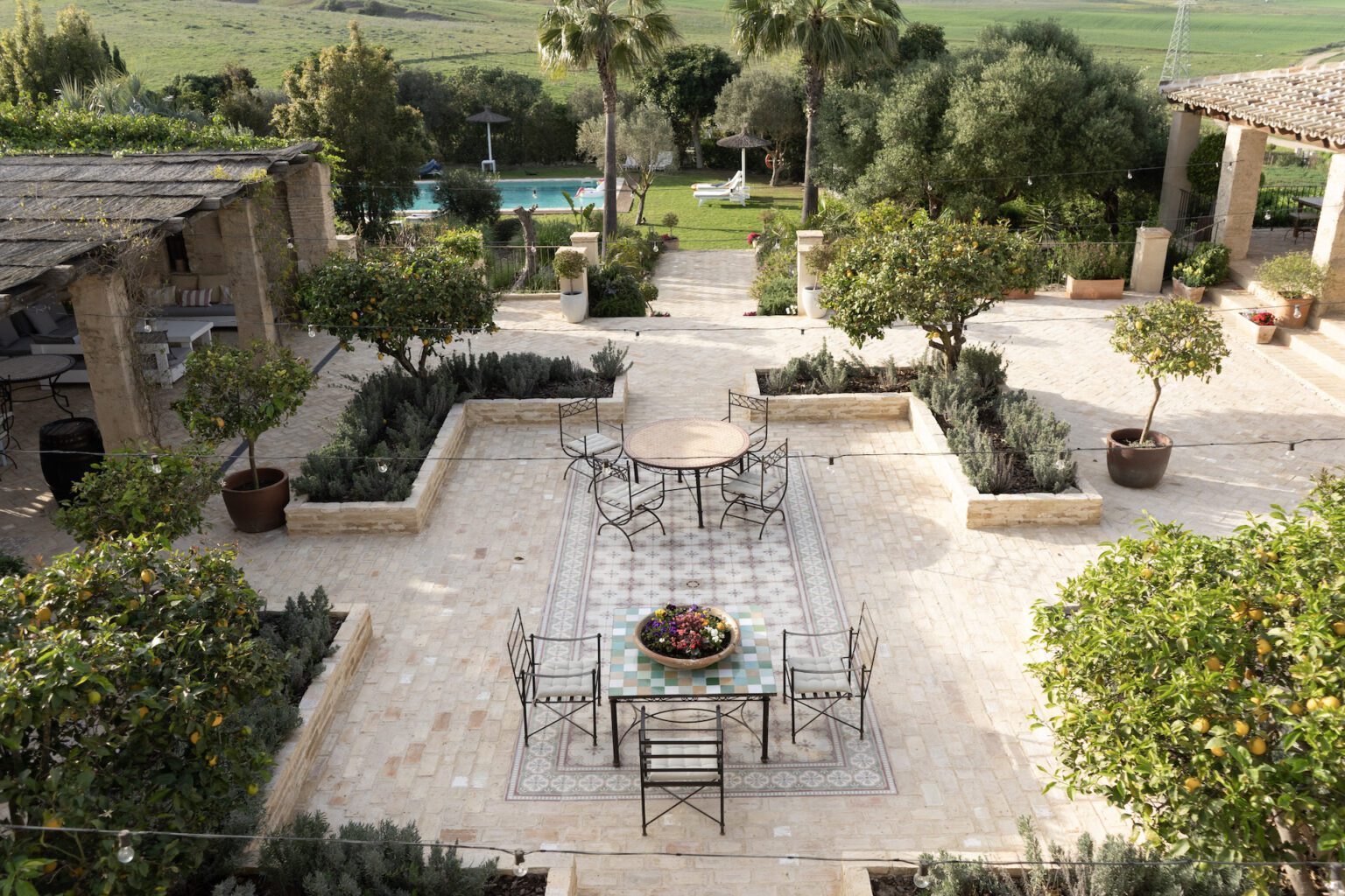 The gardens at Casa La Siesta — tiled courtyard, orange trees and one of the pools looking out over the rolling Cádiz landscape