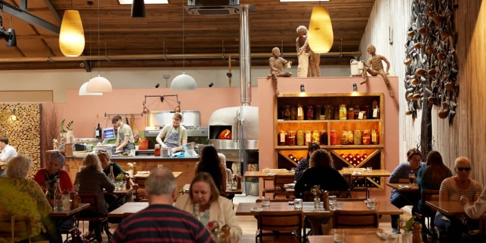 The Farm Table at Darts Farm, a timber-roofed dining room with a wood-fired oven and shelves of preserves