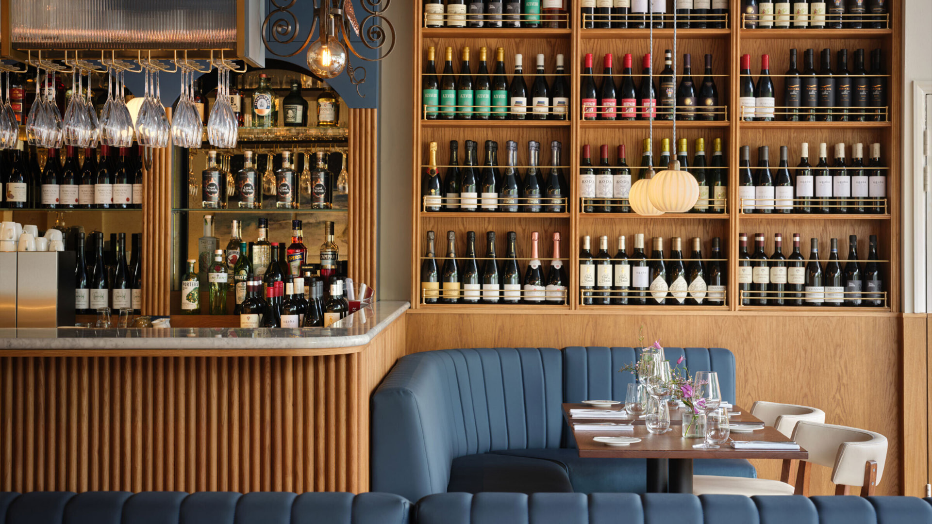 The bar at Starling, with blue banquettes, fluted oak and a full-height wine wall