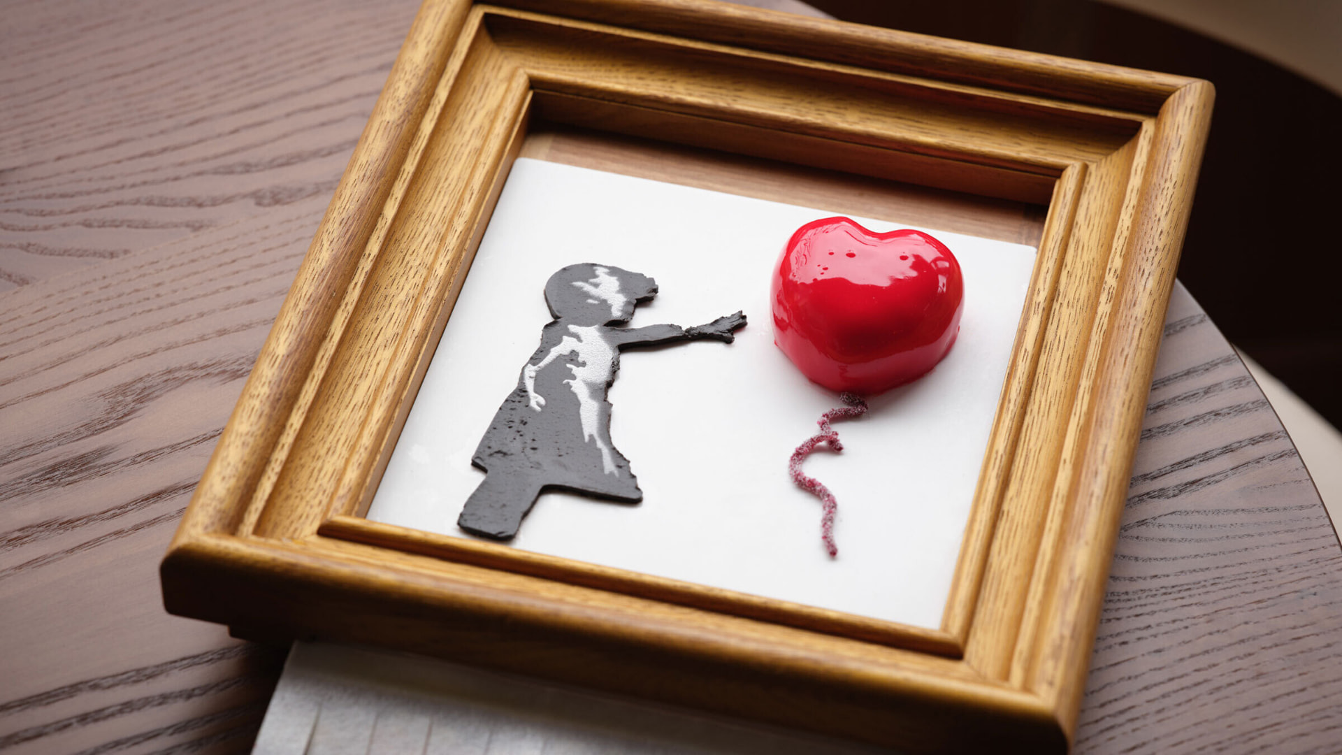 A framed dessert at Starling, a girl-with-balloon scene rendered in chocolate and a glazed red heart