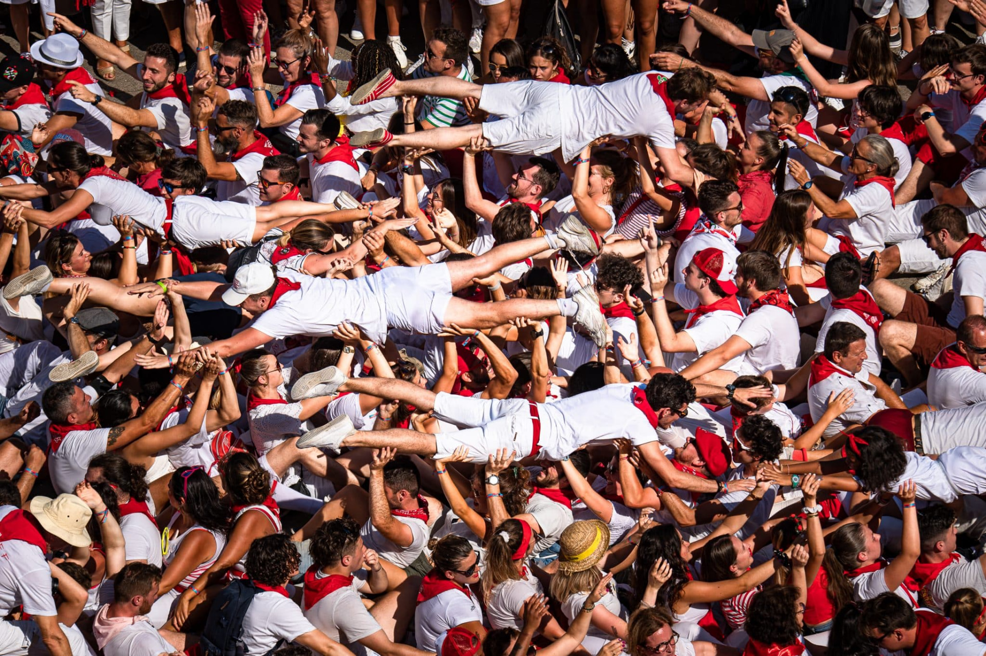 Festayres in white and red lifted horizontally above the crowd during the Fêtes de Bayonne