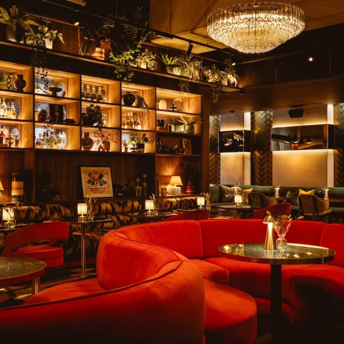 The lounge at Everyman Brentford with curved red seating and softly lit shelves