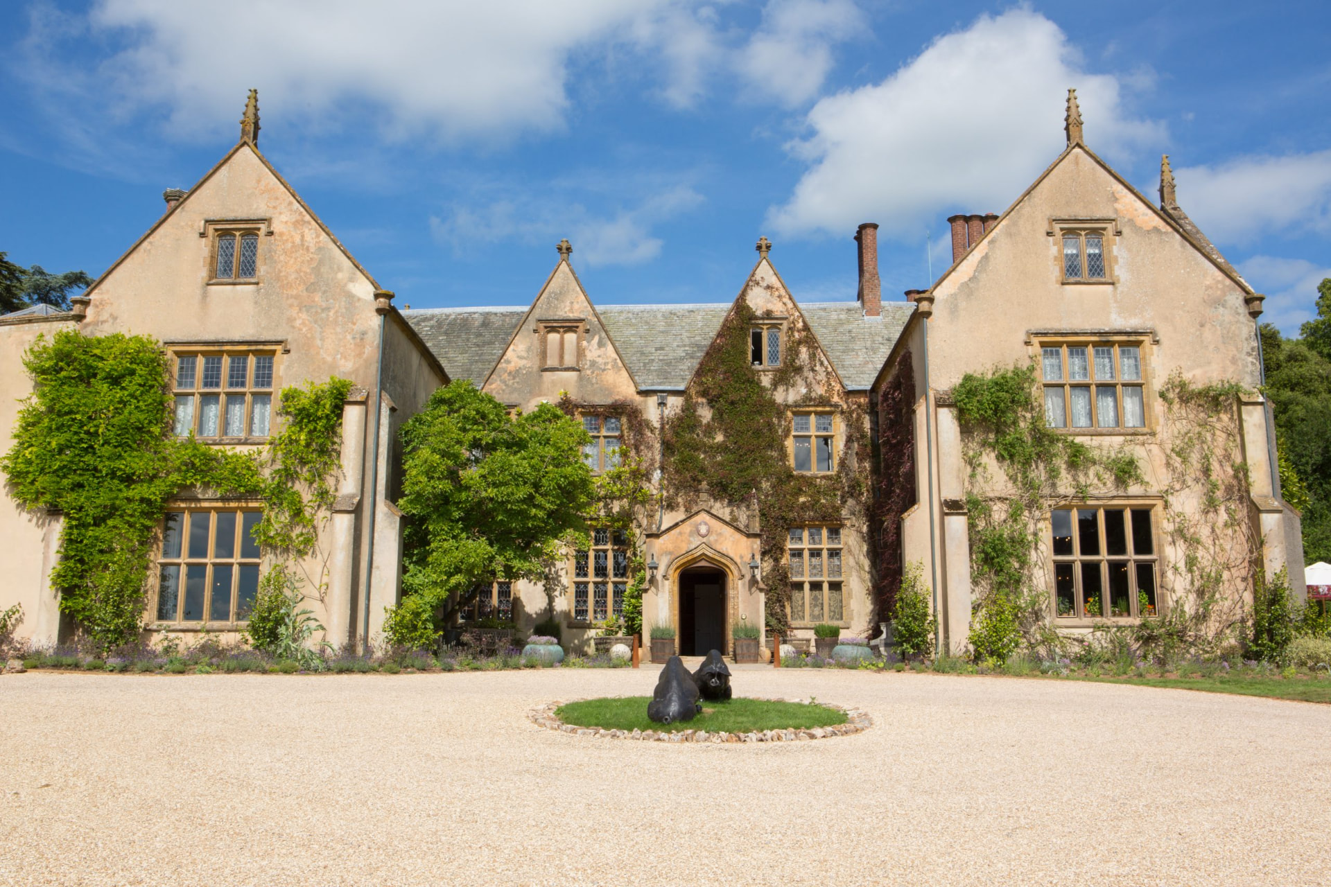 The ivy-clad Elizabethan front of The Pig at Combe across its gravel forecourt