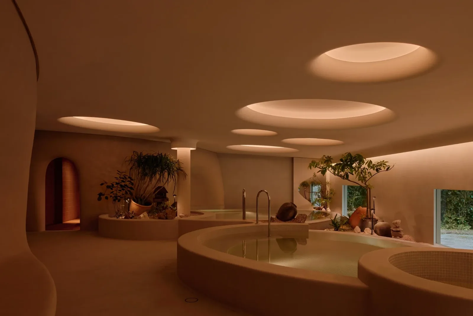 Warm communal bathing pools beneath circular skylights at Nowhere Baths in Dempsey