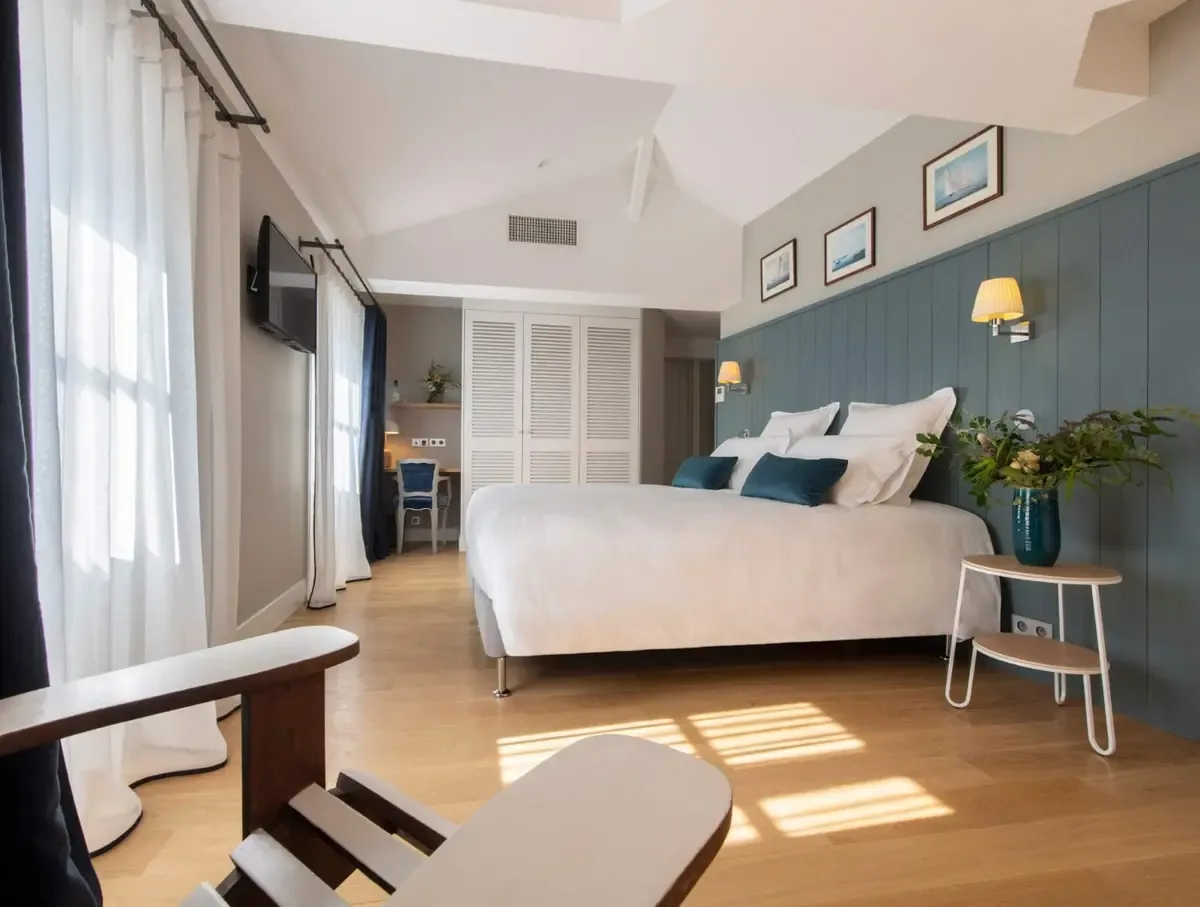 A Prestige room at Villa Grand Voile — panelled blue walls, white bed linen and oak floors under a pitched ceiling