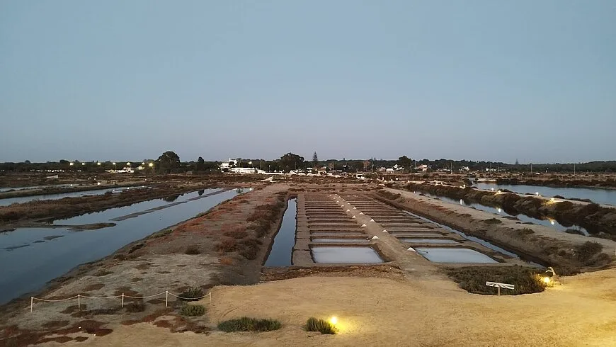 The crystallising pans at Salina Santa Teresa at blue hour, water held in shallow rectangular basins