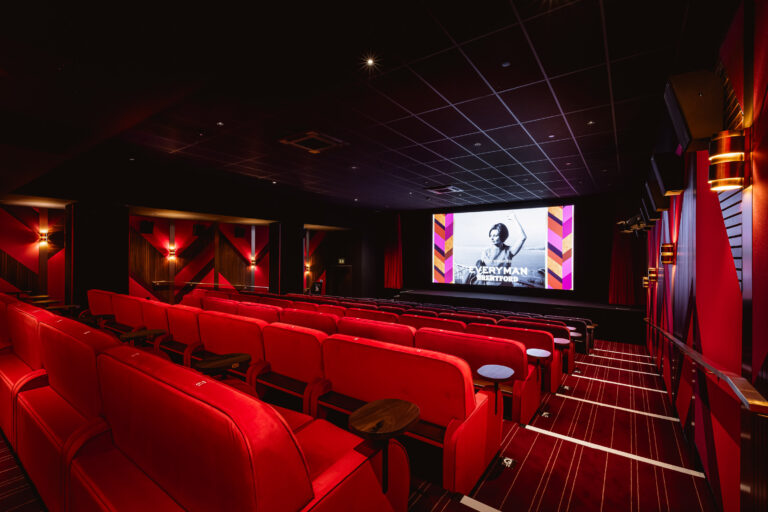 Red upholstered seats inside an intimate screening room at Everyman Brentford