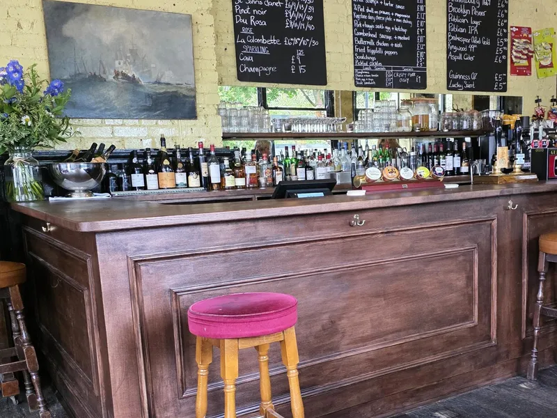 The timber bar at The Hawthorn with hand-written drinks boards and a red velvet stool