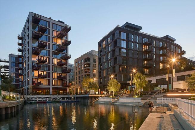 Apartment buildings beside the water at The Brentford Project at dusk