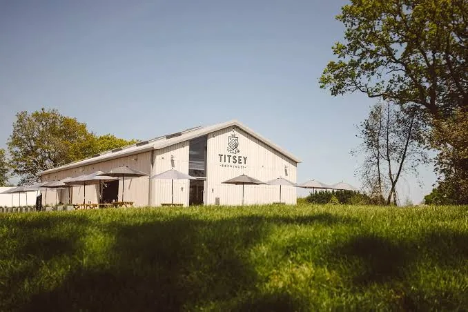 The white-boarded Titsey Brewing Co barn on the Titsey Estate, with parasols and picnic benches outside