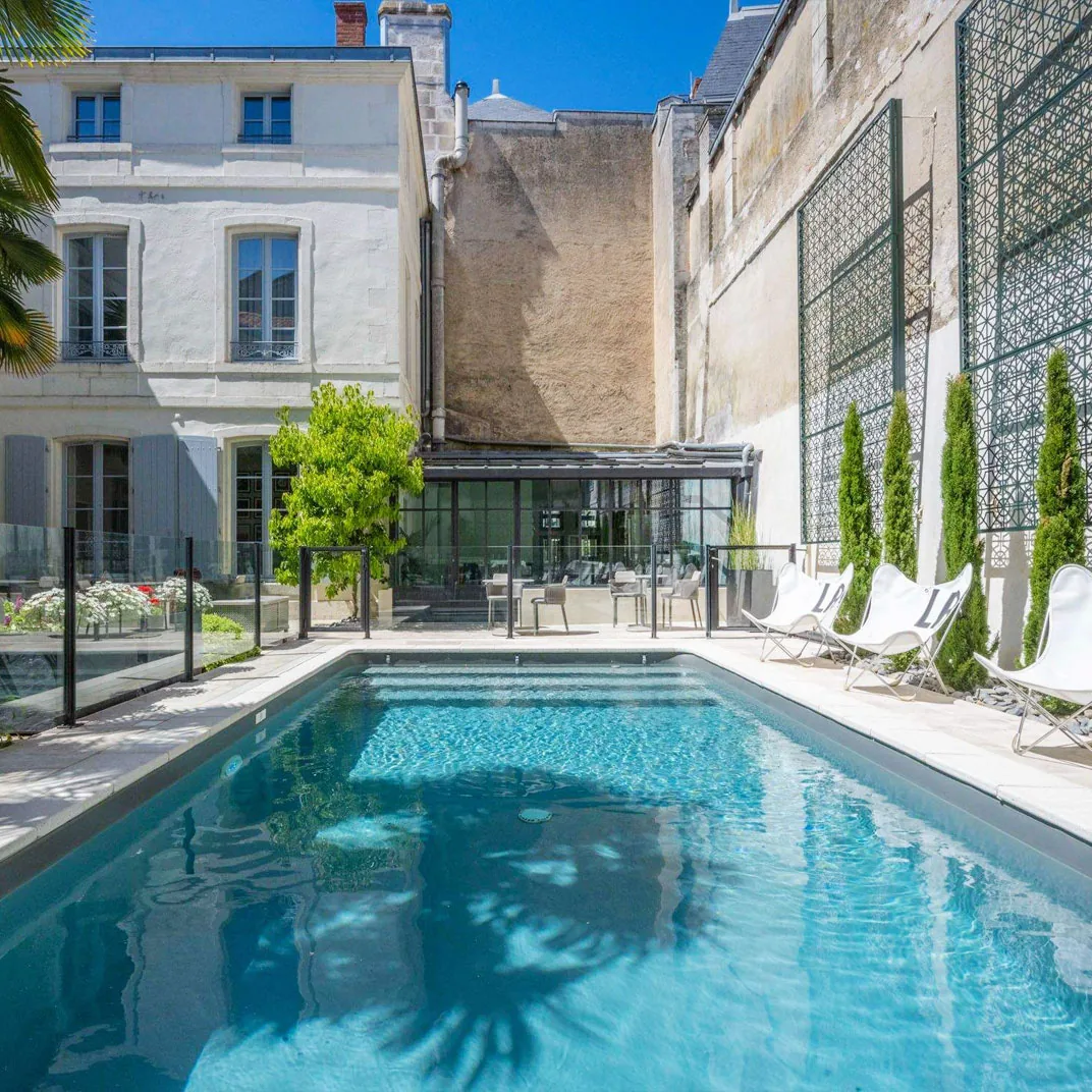 The heated outdoor pool in the planted courtyard at Villa Grand Voile, enclosed by white-stone walls