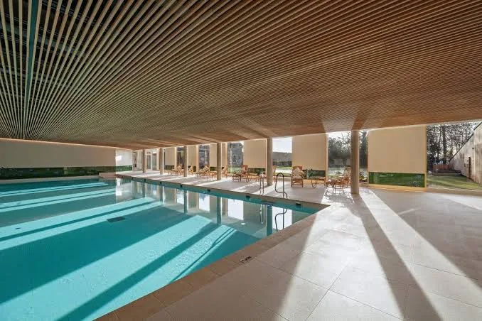 The Coach House Spa at Beaverbrook — the 20-metre indoor pool beneath a timber-slatted ceiling, with full-height windows onto the estate