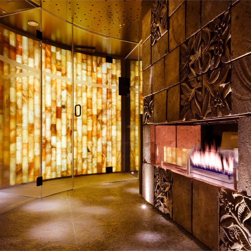 The glowing salt-brick room and carved stone fire wall in the thermal suite at Cloud Twelve