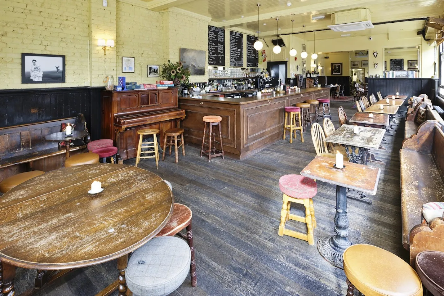 The restored bar room at The Hawthorn, with timber tables, piano, wooden counter and butter-coloured walls