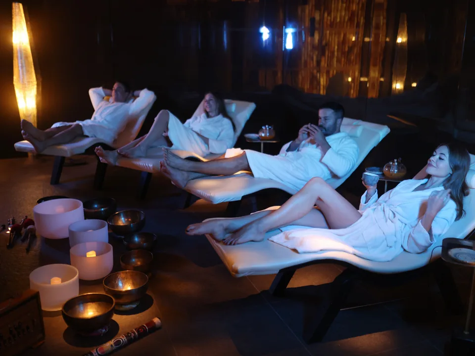 Guests in white robes on loungers in the candlelit relaxation room at Cloud Twelve, with singing bowls on the floor