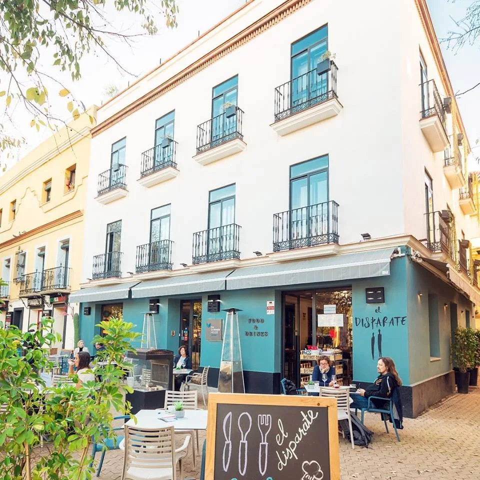 El Disparate on the corner of Alameda de Hércules — teal-painted ground floor, terrace tables and balconies above