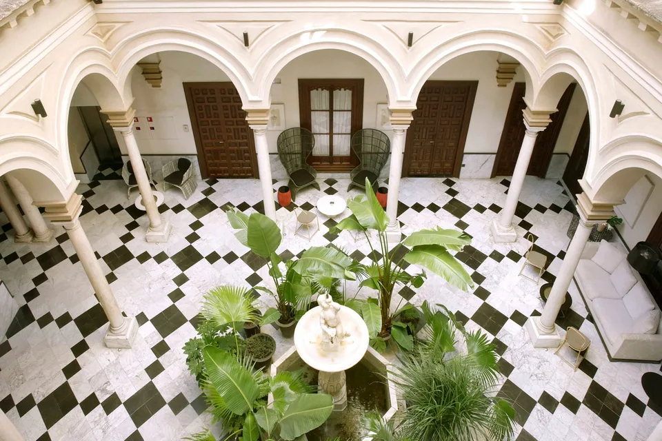 The main courtyard at Palacio Villapanés — marble columns, chequerboard floor and a central fountain