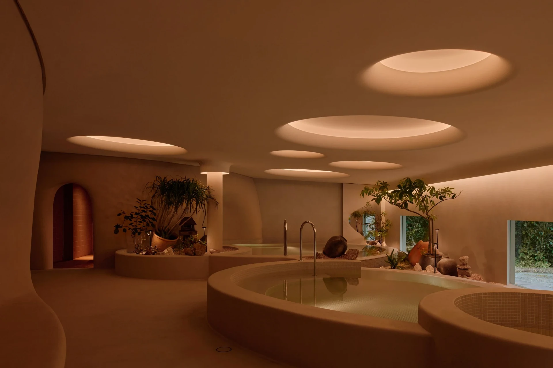 Warm communal bathing pools beneath circular skylights at Nowhere Baths in Dempsey