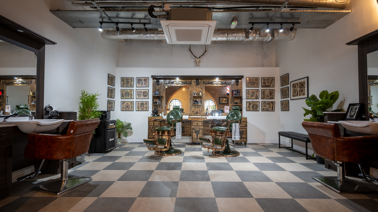 The barber room at Old Station Quarter, with green leather chairs and framed tattoo flash on the walls