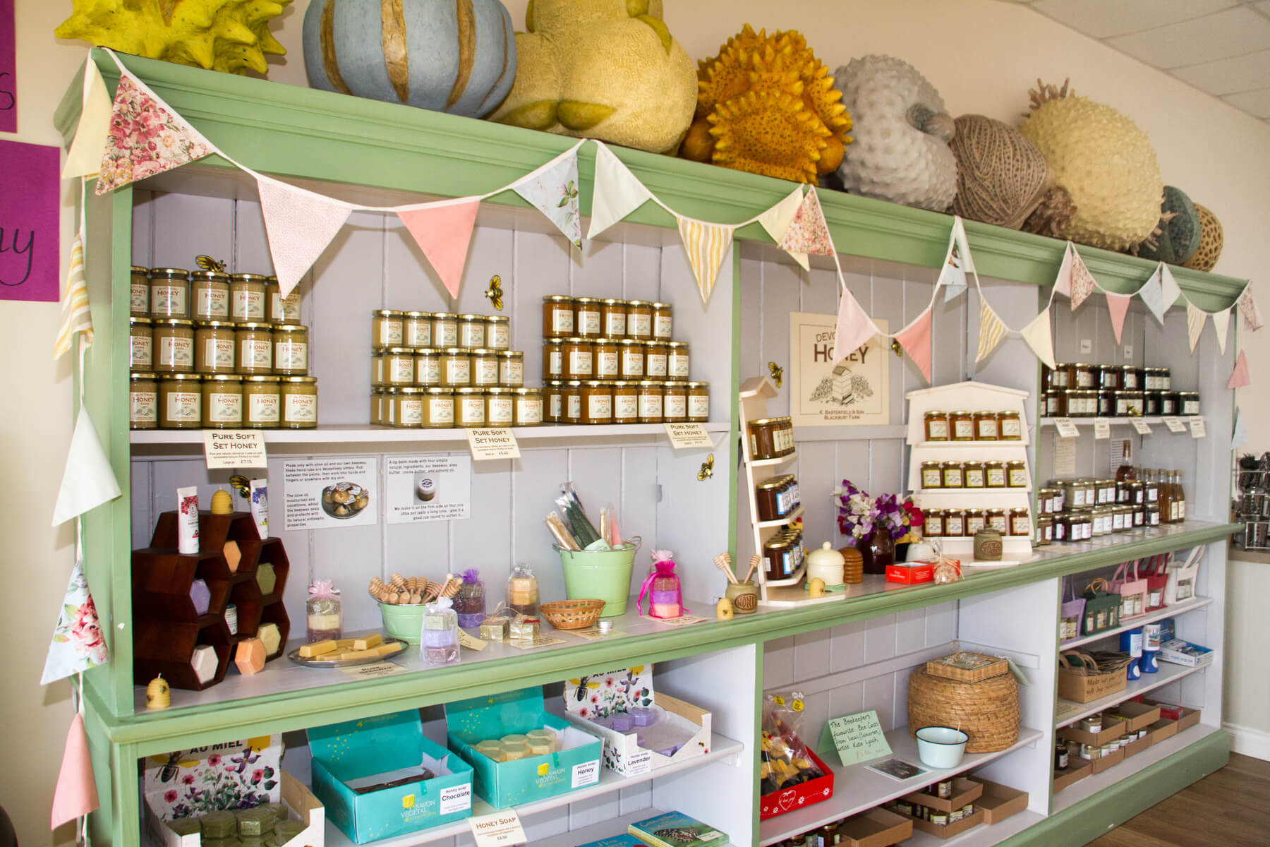 The honey shop at Blackbury Honey Farm, a green dresser lined with jars of honey and hive products