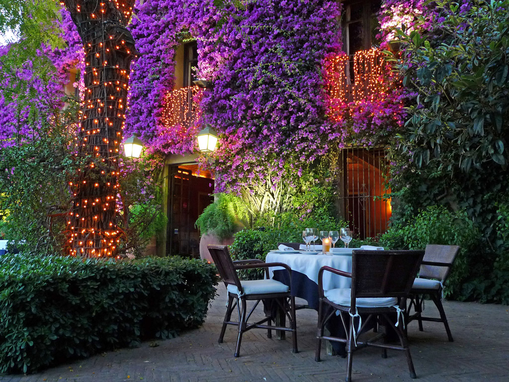The garden terrace at Can Travi Nou at night, with outdoor tables, flowers and warm lights