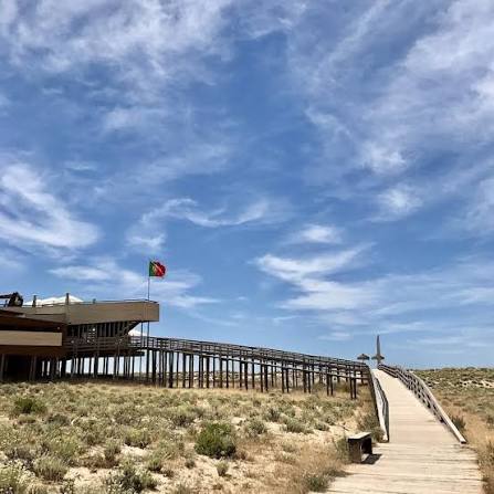 The wooden walkway over the dunes leading to 2 Passos under a blue sky