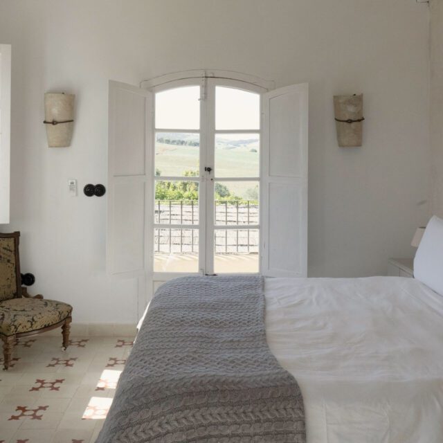 A bedroom at Casa La Siesta — white shutters opening onto the Cádiz countryside