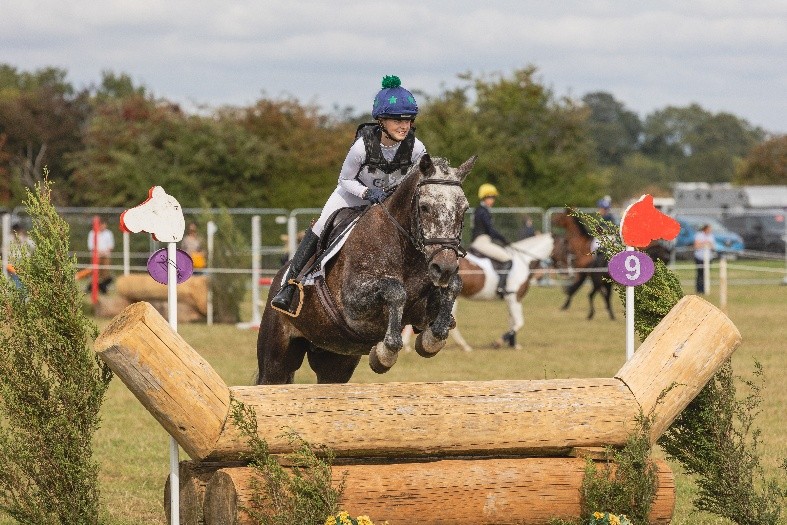 A rider clearing a rustic log fence in the showjumping ring at Moreton Show