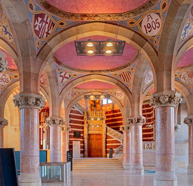 The ornate entrance hall at Sant Pau Recinte Modernista with tiled vaulted ceilings, stone columns and a staircase beyond