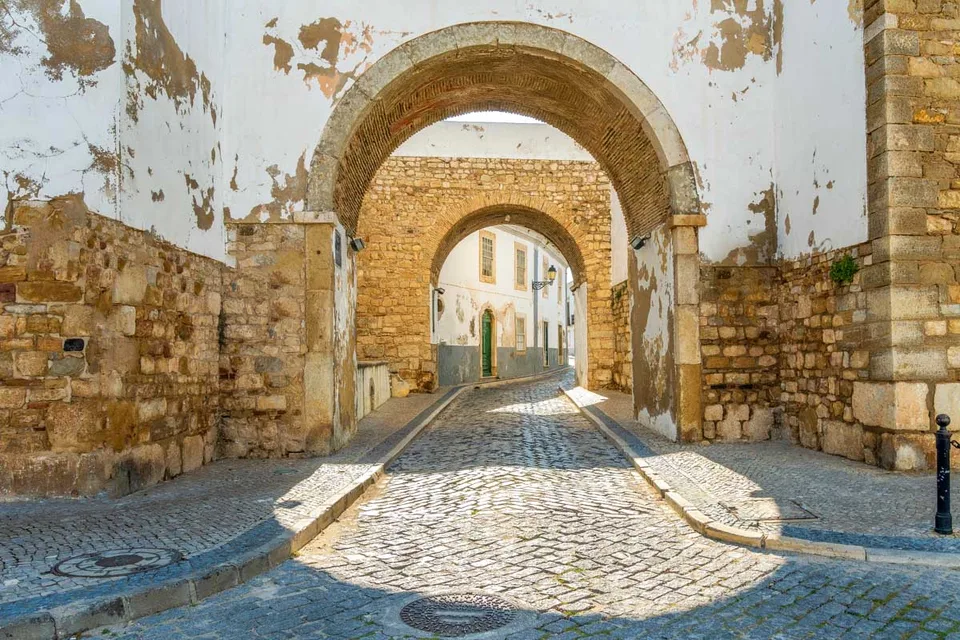 Double stone arches over a cobbled lane in Faro's walled old town