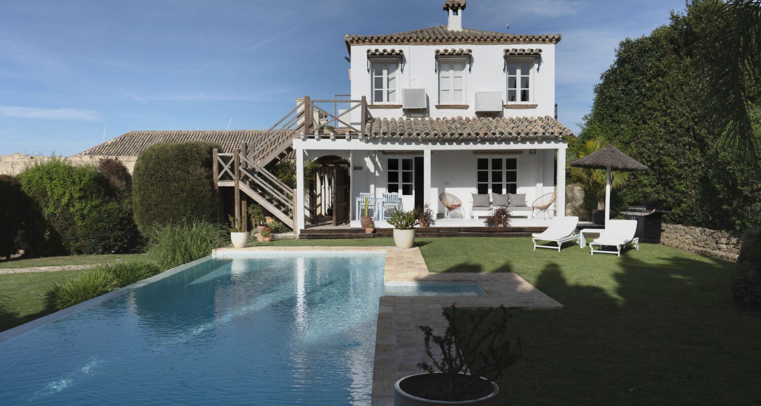 The white house at Casa La Siesta with its long pool and sun loungers on the lawn