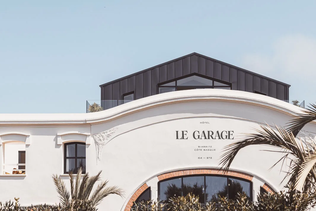 Hôtel Le Garage Biarritz — the curved white facade with the hotel's lettering and the arched brick openings below